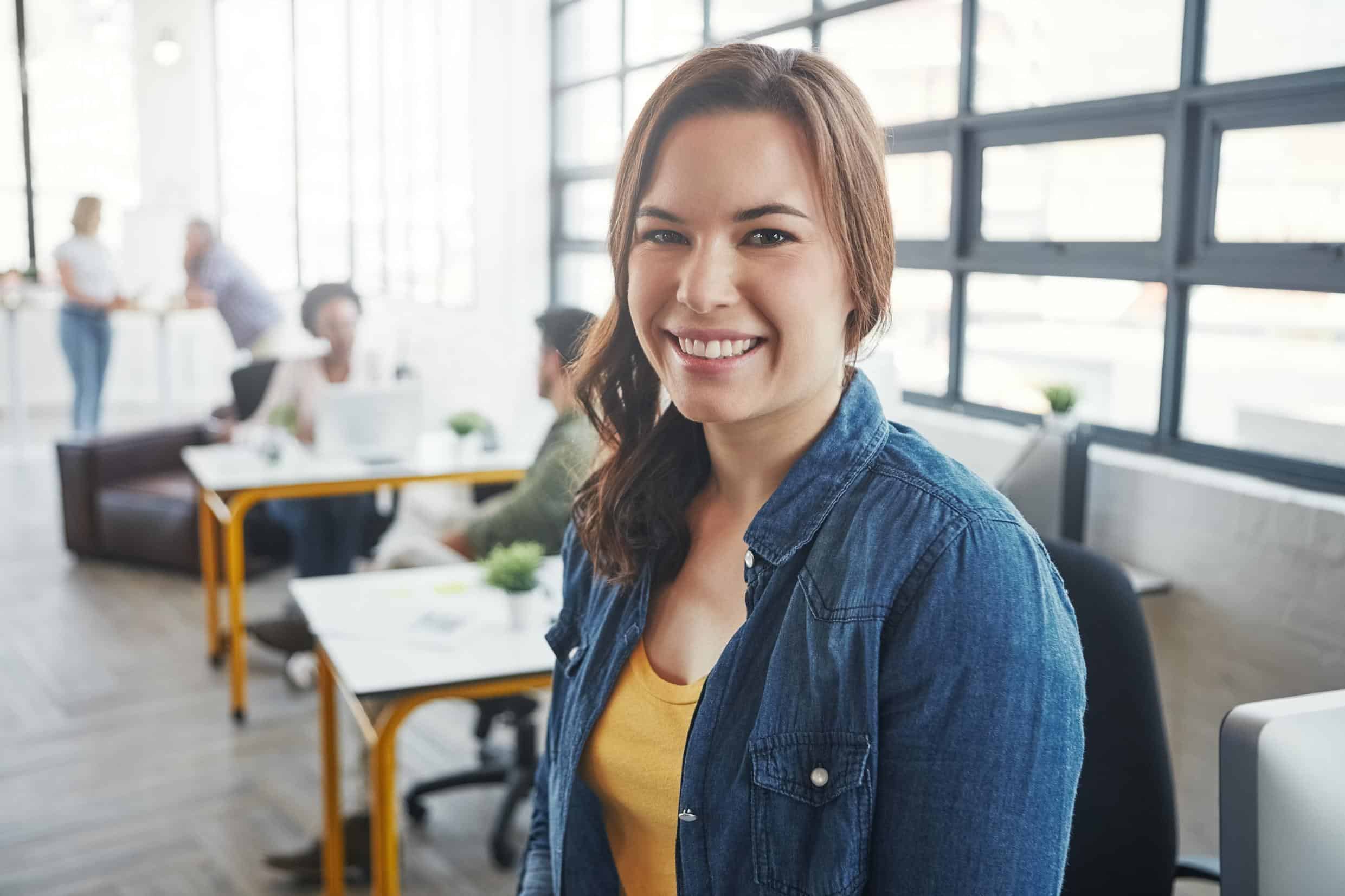 1. Mujer sonriendo en oficina moderna, ambiente de trabajo colaborativo y circular.